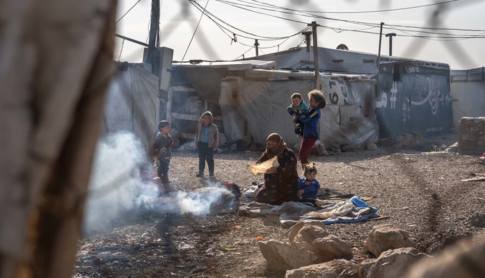 Frau und Kinder sitzen in einem Flüchtlingscamp im Libanon an Feuer