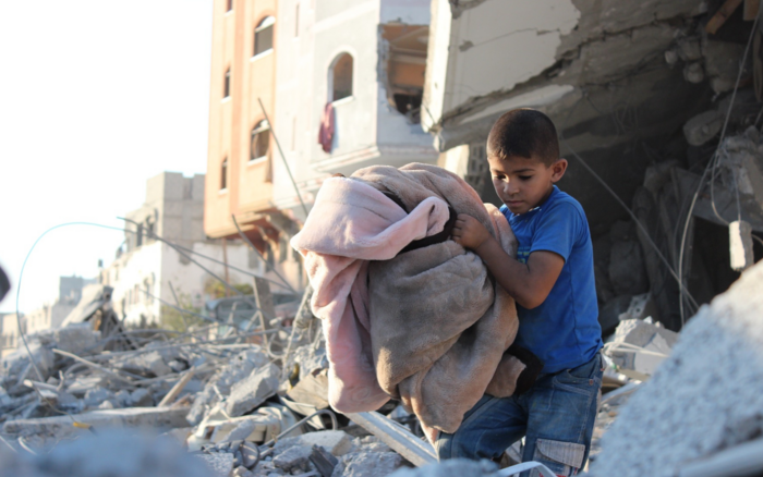 Ein Kind mit einer Decke läuft im Gazastreifen über Trümmer