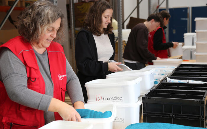 Vier Menschen stehen in einer Reihe und packen Materialien in weiße Boxen mit humedica-Logo