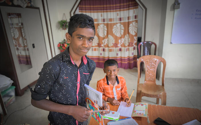 Zwei Jungen arbeiten an ihren Hausaufgaben und schauen in die Kamera