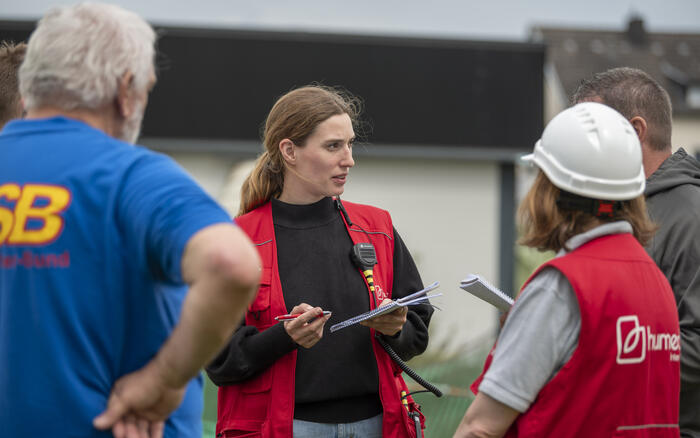Eine Frau mit humedica-Weste spricht zu Einsatzkräften