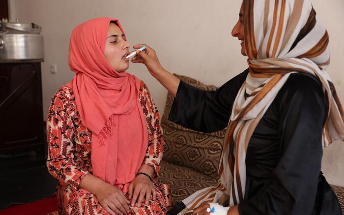 Eine Frau misst einer anderen mit einem Fieberthermometer im Mund die Temperatur