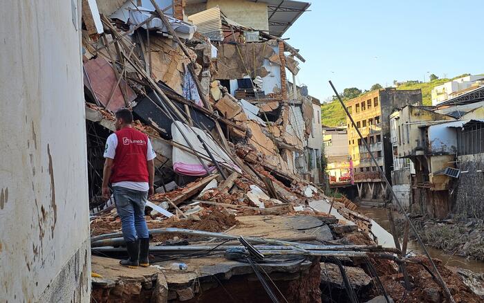 Ein Mann mit roter humedica-Weste steht nach einer Überschwemmung in Brasilien in einem zerstörtem Gebäudekomplex.