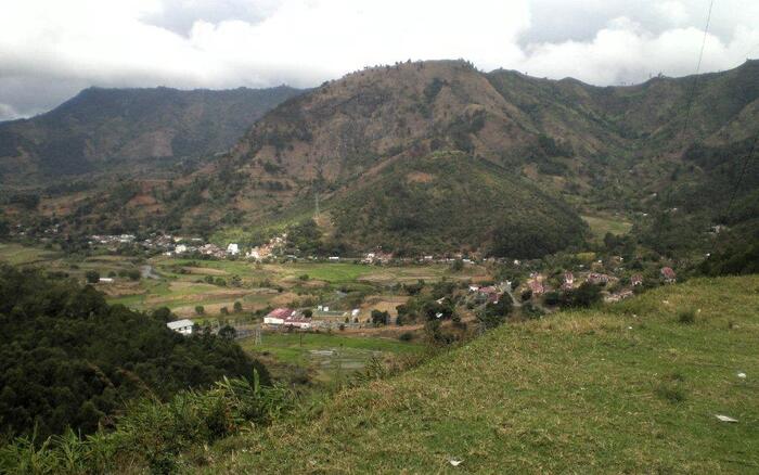In einer grünen Hügellandschaft befinden sich Häuser.