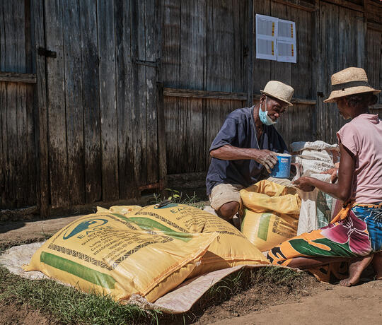 Mann verteilt Lebensmittel an eine Frau in Madagaskar