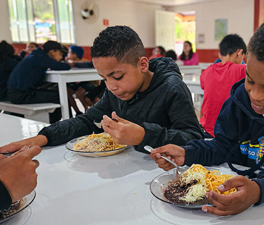 Kinder sitzen am Tisch und essen ihre Mahlzeit