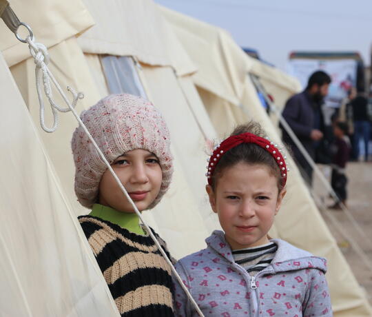 Zwei Mädchen stehen vor einem Zelt in einem Geflüchtetencamp in Syrien