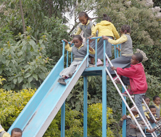Kinder auf einer Rutsche auf dem Spielplatz des Kindergartens