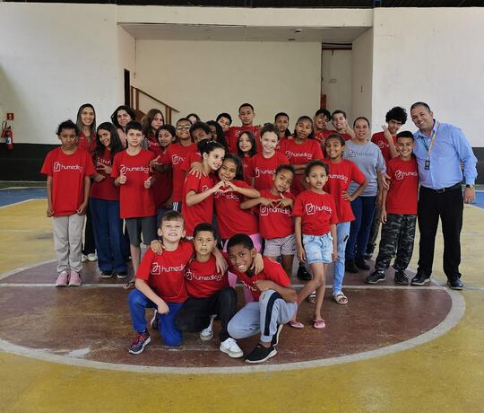 Kinder mit rotem humedica-T-Shirt stehen in einer Turnhalle
