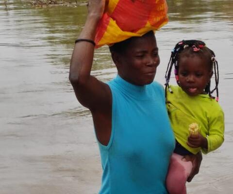 Frau mit Kind steht hüfthoch im Wasser nach Überflutung