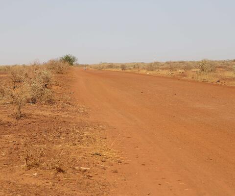 Karge rötliche Landschaft im Niger mit einer Straße aus rotem Sand