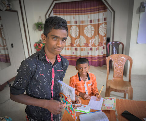 Zwei Jungen arbeiten an ihren Hausaufgaben und schauen in die Kamera