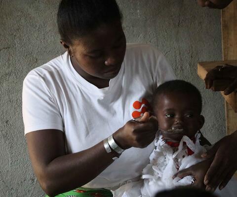 Eine Frau füttert ein kleines Kind, das auf ihrem Schoß sitzt