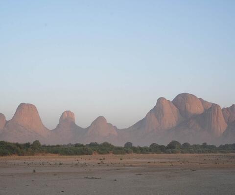Die markanten Taka-Berge im Sudan erheben sich in den blauen Himmel. Davor ist die Landschaft flach.