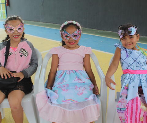 Drei Mädchen sitzen mit Augenmasken in einer Stuhlreihe