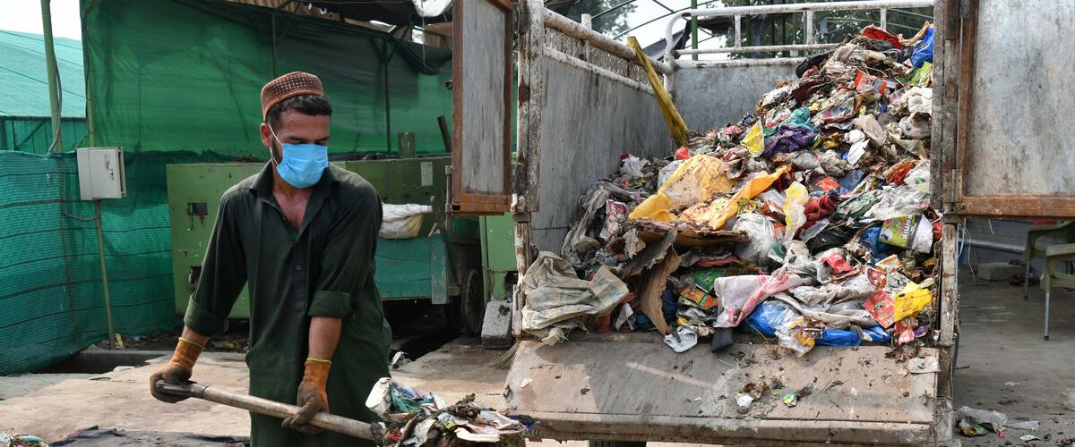 Mann lädt Müll auf einen Hänger in Pakistan