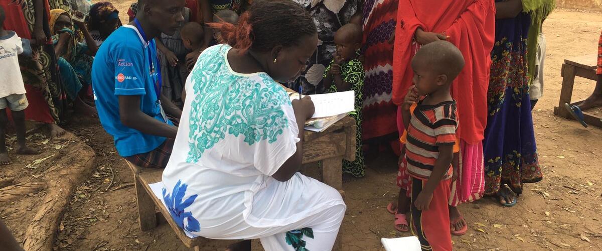 Kind steht in umgeben von Frauen auf Babywaage in Kenia