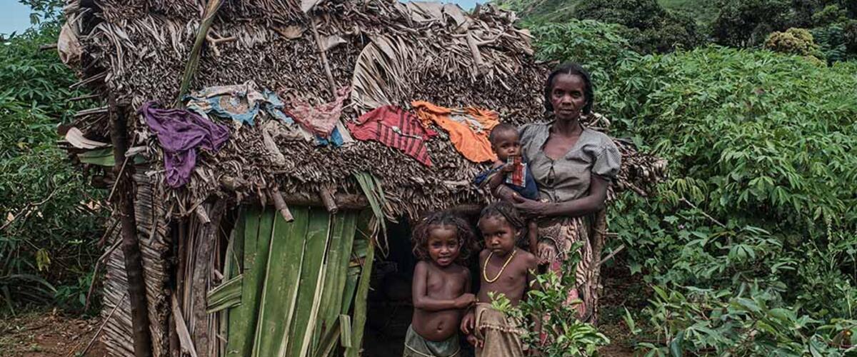 Frau mit drei Kindern vor einer Hütte in Madagaskar