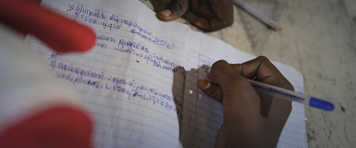 Kinderhand schreibt mit Stift etwas in Schreibheft