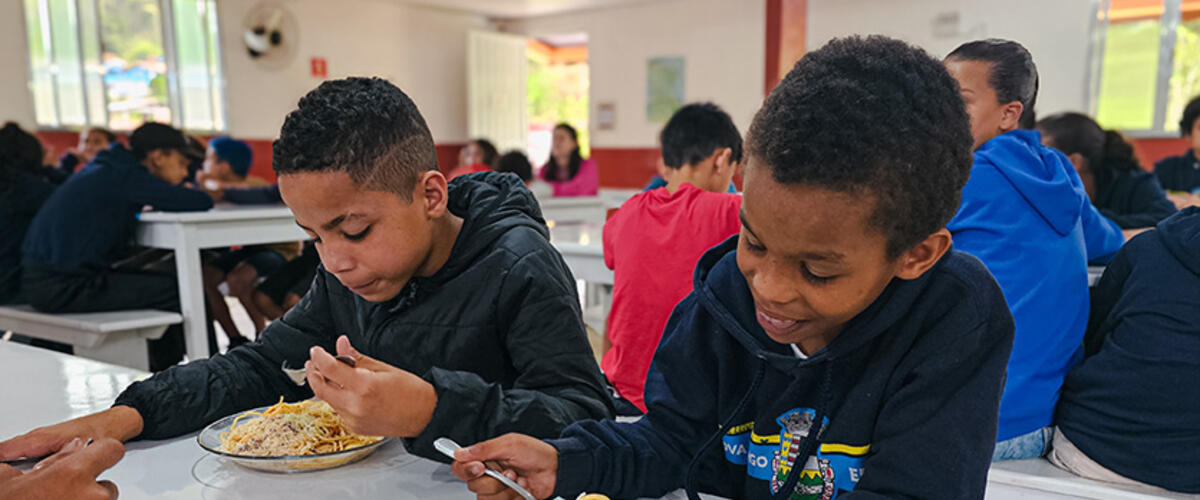 Kinder sitzen am Tisch und essen ihre Mahlzeit