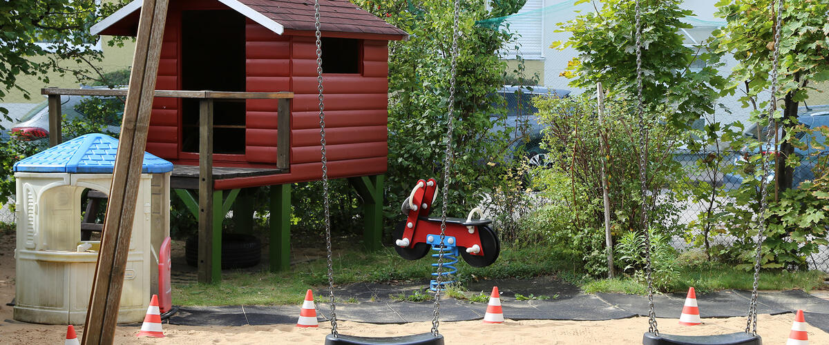 Schaukeln und Spielehaus auf einem Sandplatz