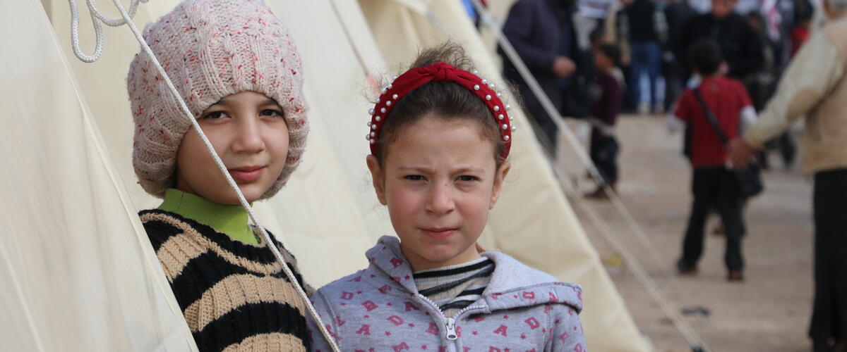 Zwei Mädchen stehen vor einem Zelt in einem Geflüchtetencamp in Syrien