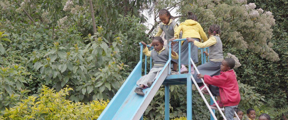 Kinder auf einer Rutsche auf dem Spielplatz des Kindergartens
