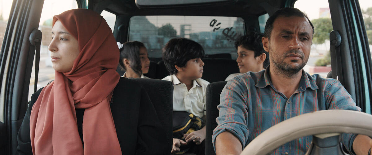 Filmszene: Eine Familie sitzt im Auto, Mann und Frau vorn, drei Kinder hinten