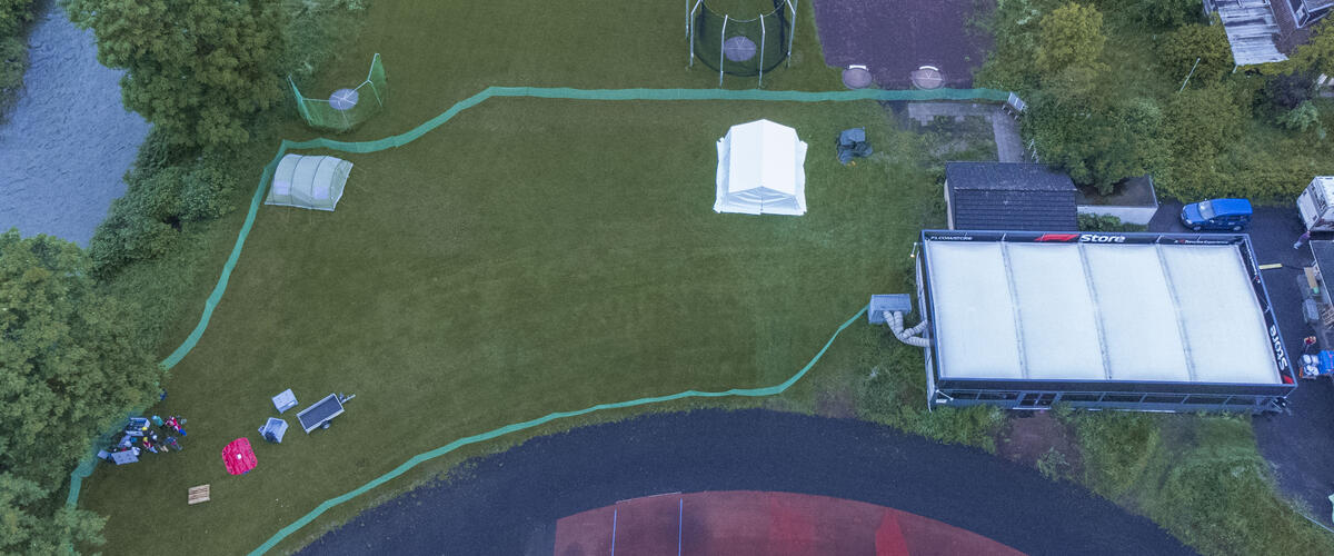 Luftbildaufnahme einer abgegrenzten Wiese mit Zelt