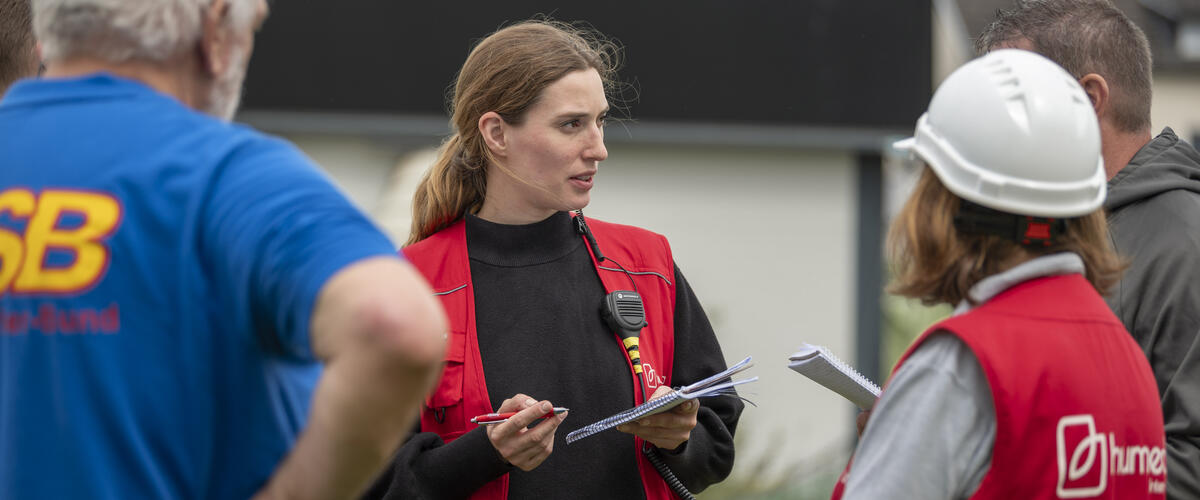 Eine Frau mit humedica-Weste spricht zu Einsatzkräften