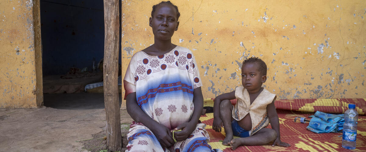 Eine schwangere Frau sitzt vor einem Gesundheitszentrum in Äthiopien, neben ihr ein Junge