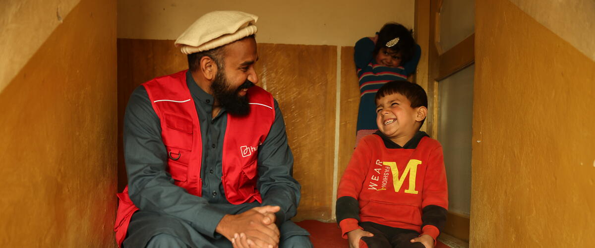 Ein Mann mit roter humedica-Weste und ein Junge sitzen auf einer Treppe und lachen