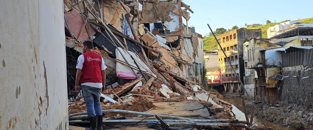 Ein Mann mit roter humedica-Weste steht nach einer Überschwemmung in Brasilien in einem zerstörtem Gebäudekomplex.