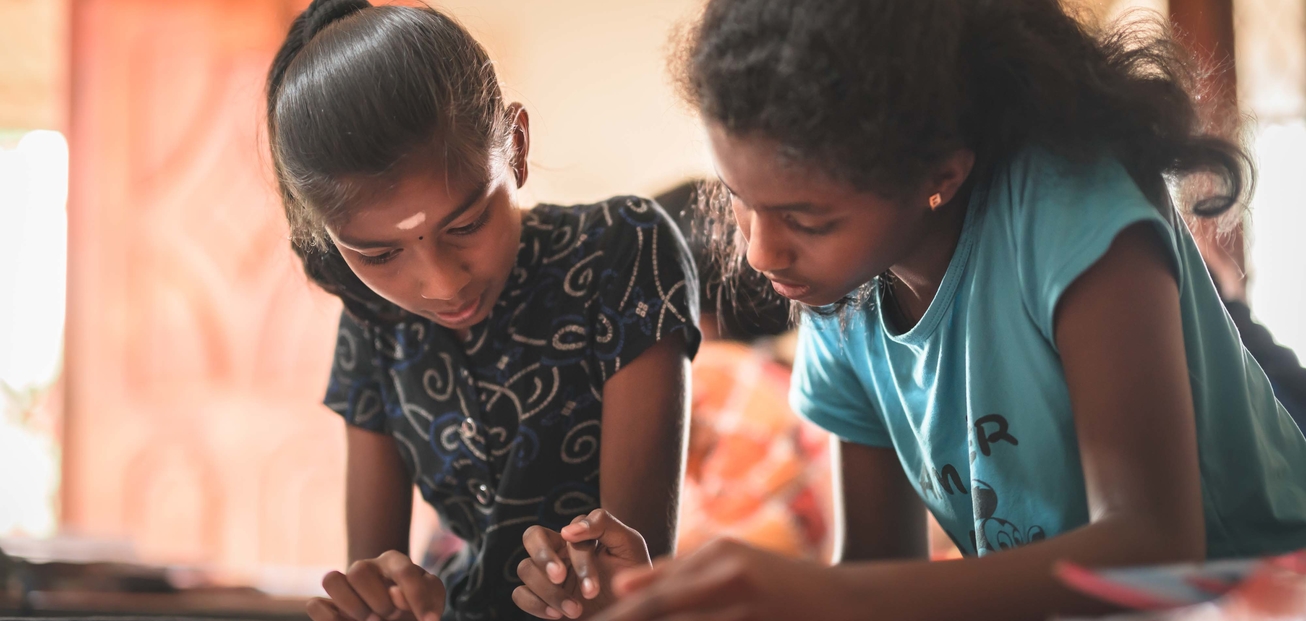Zwei Mädchen schauen auf ein Heft in Sri Lanka