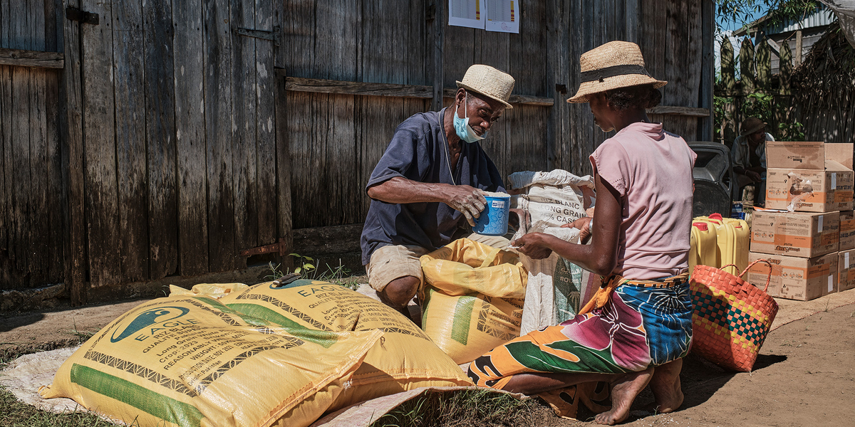 Mann verteilt Lebensmittel an eine Frau in Madagaskar