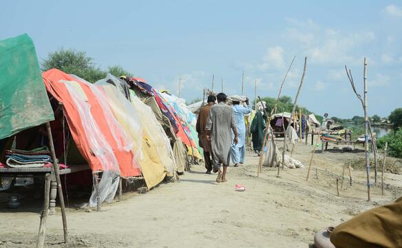 Männer laufen an Zeltsiedlung in Pakistan vorbei