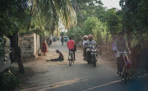 Junge bahnt sich den Weg auf seinem Fahrrad über eine Straße in Sri Lanka