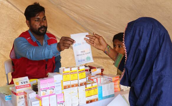 Mitarbeiter überreicht pakistanischer Frau einen Zettel