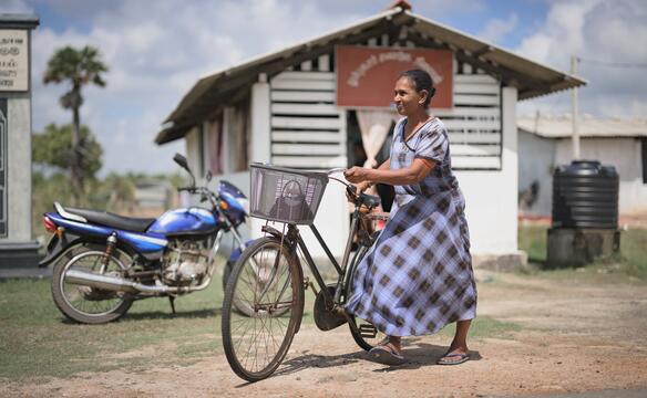 Frau schiebt ihr Fahrrad vor Krankenstation in Sri Lanka