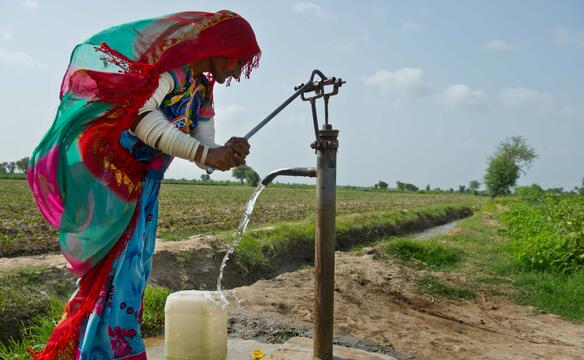 Frau in Pakistan benutzt Handpumpe