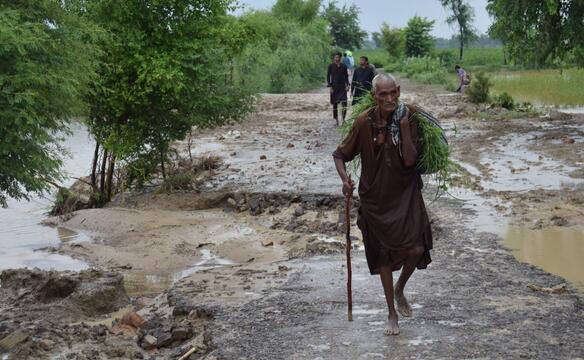 Älterer Herr geht durch den Schlamm in Pakistan