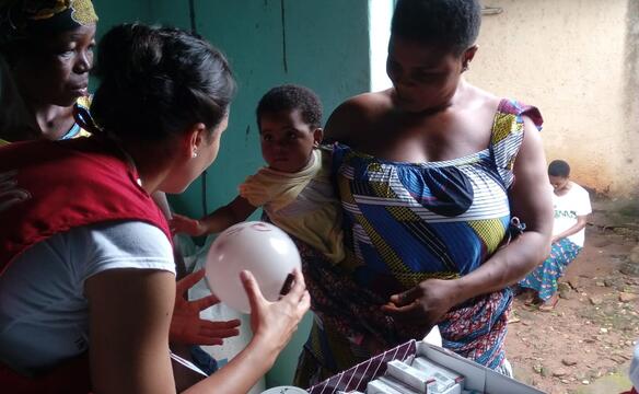 Helferin übergibt KLeinkind Lufballon in Togo