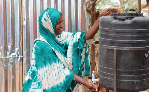 Eine Frau in Somalia wäscht sich an einem Wasserfass die Hände 