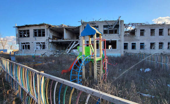 Klettergeruest steht vor einem zerstoerten Haus in der Ukraine