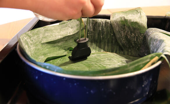 Bananenblatt wird in Backform mit Oel eingepinselt