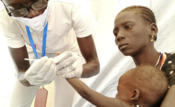 Arzt-untersucht-unterernaehrten-Saeugling-auf-dem-Schoss-seiner-Mutter