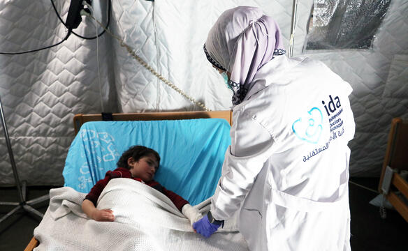 Eine Medizinerin steht neben einem Mädchen im Krankenbett