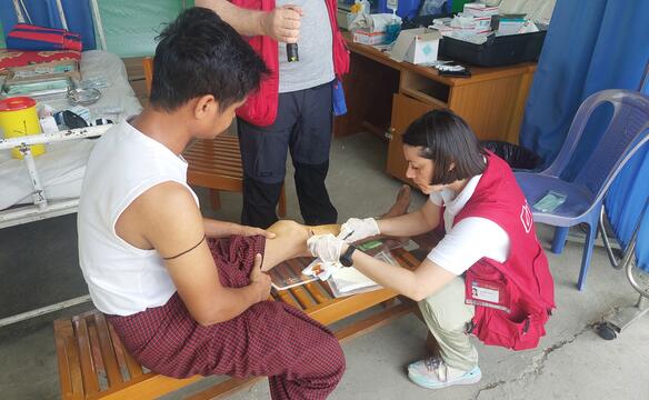 Die Wunde am Bein eines Mannes wir von einer humedica-Einsatzkraft versorgt