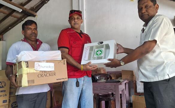 Ein humedica-Mitarbeiter übergibt eine Erste-Hilfe-Box an den Mitarbeiter eines Notfallcamps nach der Wirbelsturm in Sri Lanka