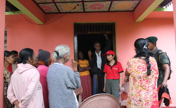 Eine Frau mit rotem humedica-T-Shirt steht in einer Tür und spricht zu einer Gruppe Frauen davor